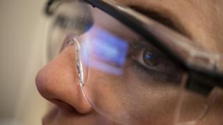 A close up image on the eyes of a research student wearing safety glasses